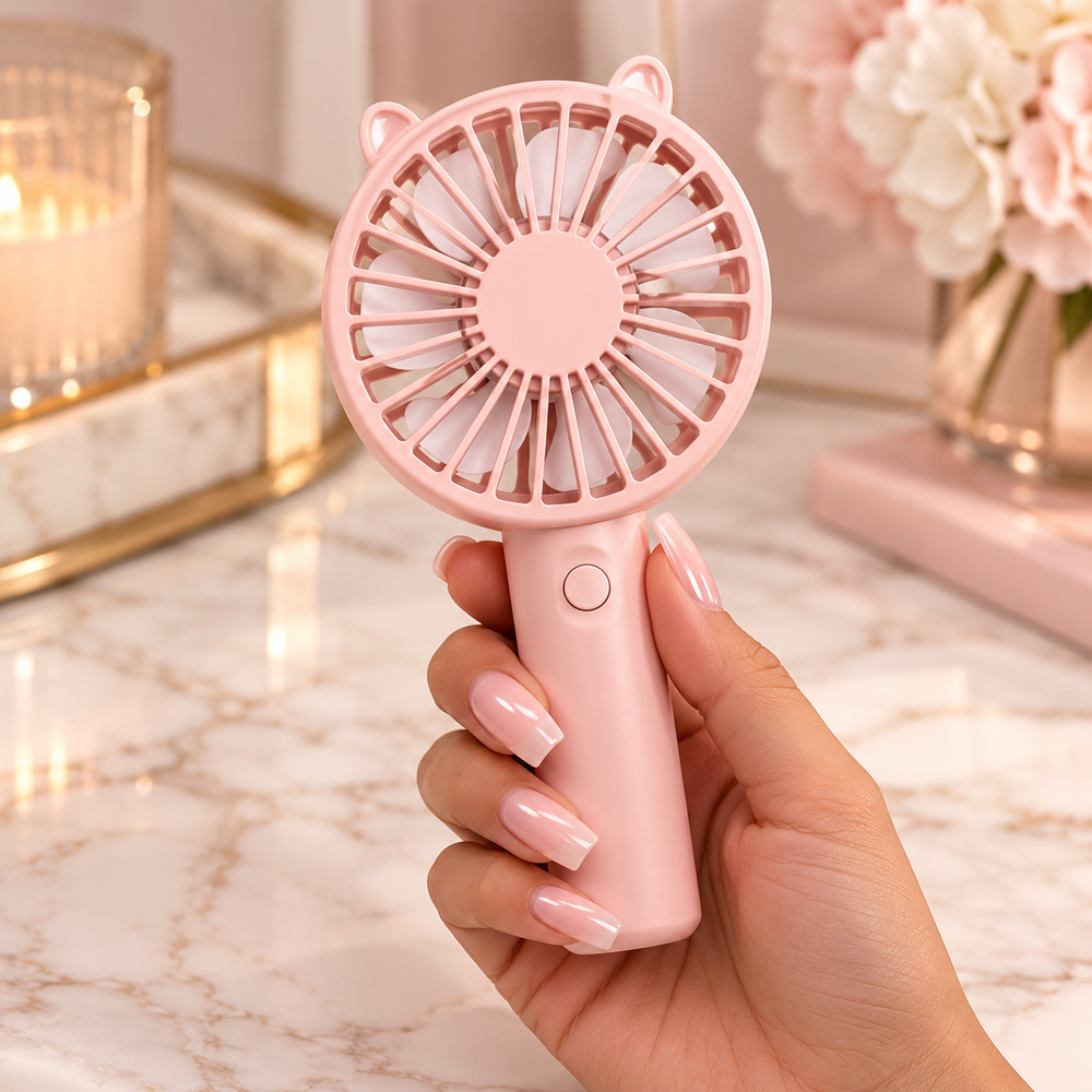 Blush pink handheld portable mini fan shown in hand to demonstrate its compact size